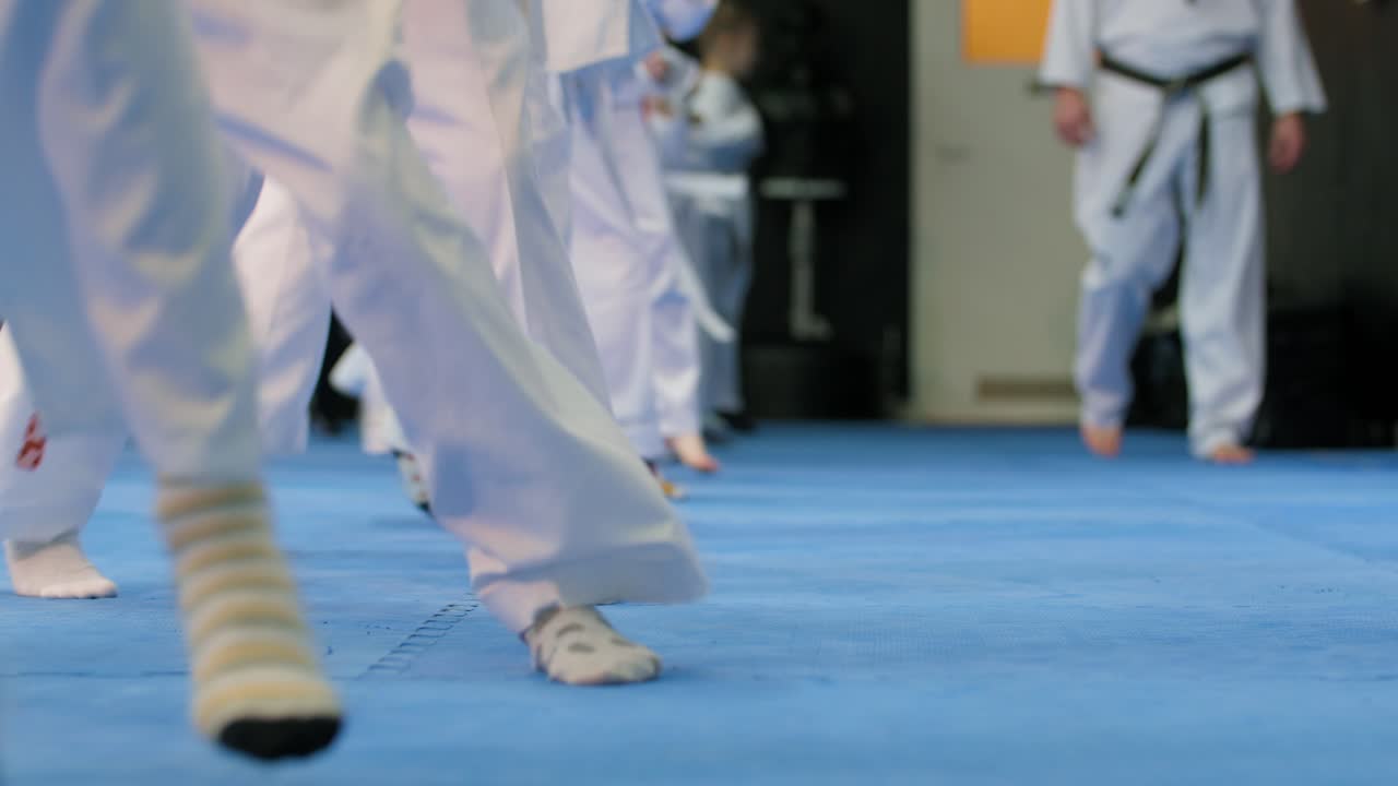 niños en kimono blanco saltando en cámara lenta entrenando judo en una estera de tatami