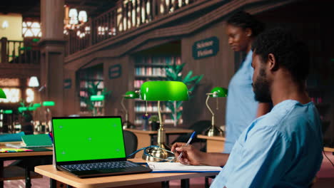 african american male nurse studies anatomy textbooks next to green screen