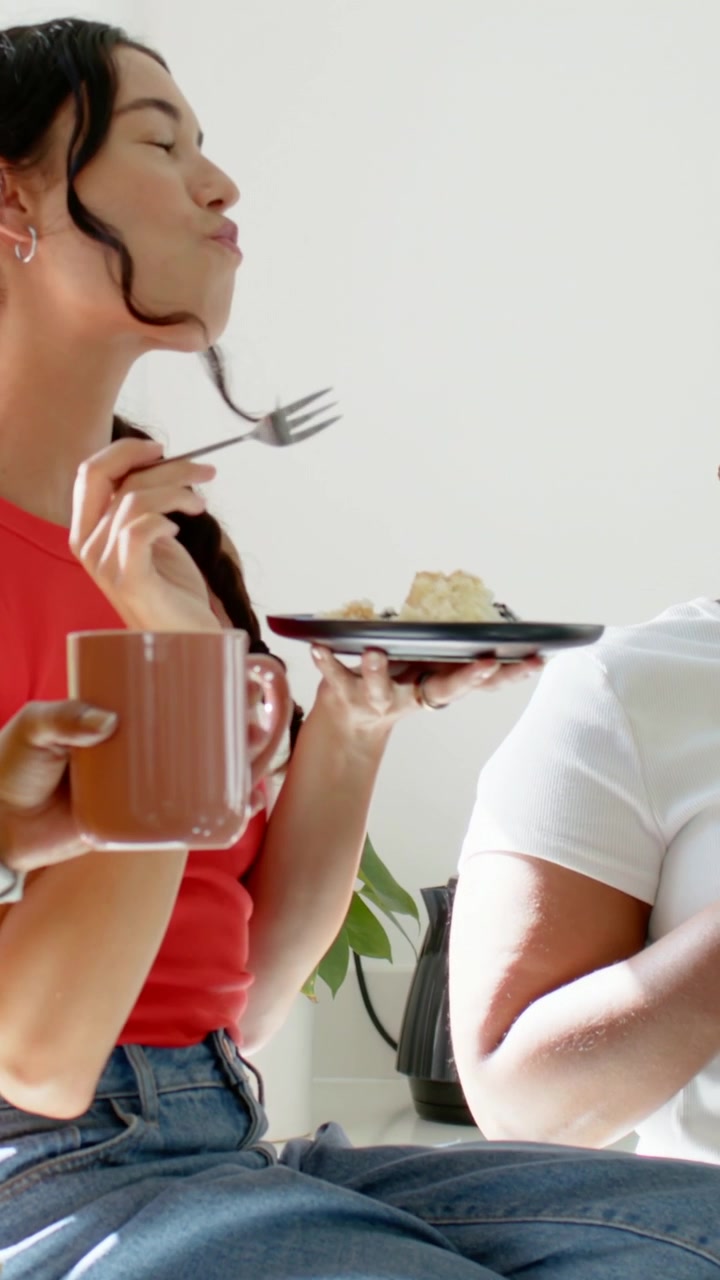 Video vertical: Amigo ofreciendo un plato, mujer con top rojo y jeans sirviendo postre para probar en casa.