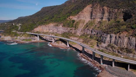 Aerial-view-cars-on-Sea-Cliff-Bridge,-sunny-day,-grand-pacific-drive,-New-South-Wales,-Australia---panorama-drone-shot