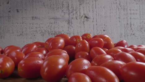 muchos tomates rojos maduros sobre una superficie de madera en la cocina, listos para cocinar