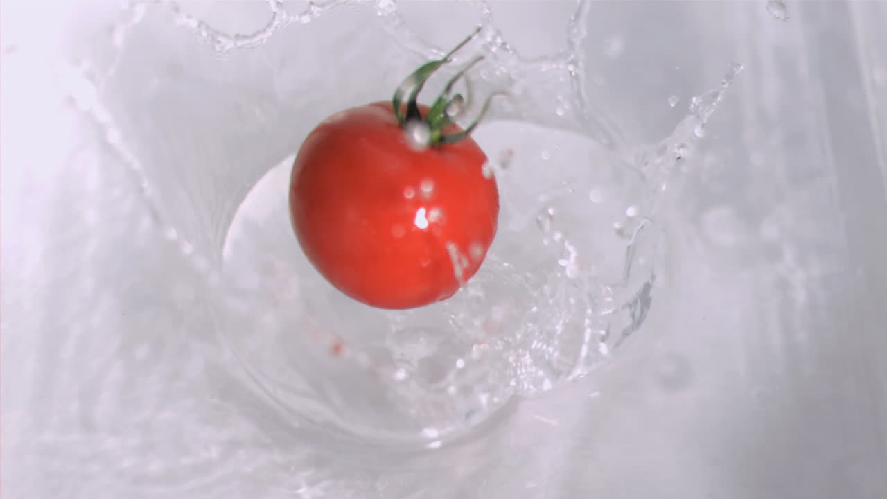 토마토가 슈퍼 슬로 모션으로 물에 떨어집니다.