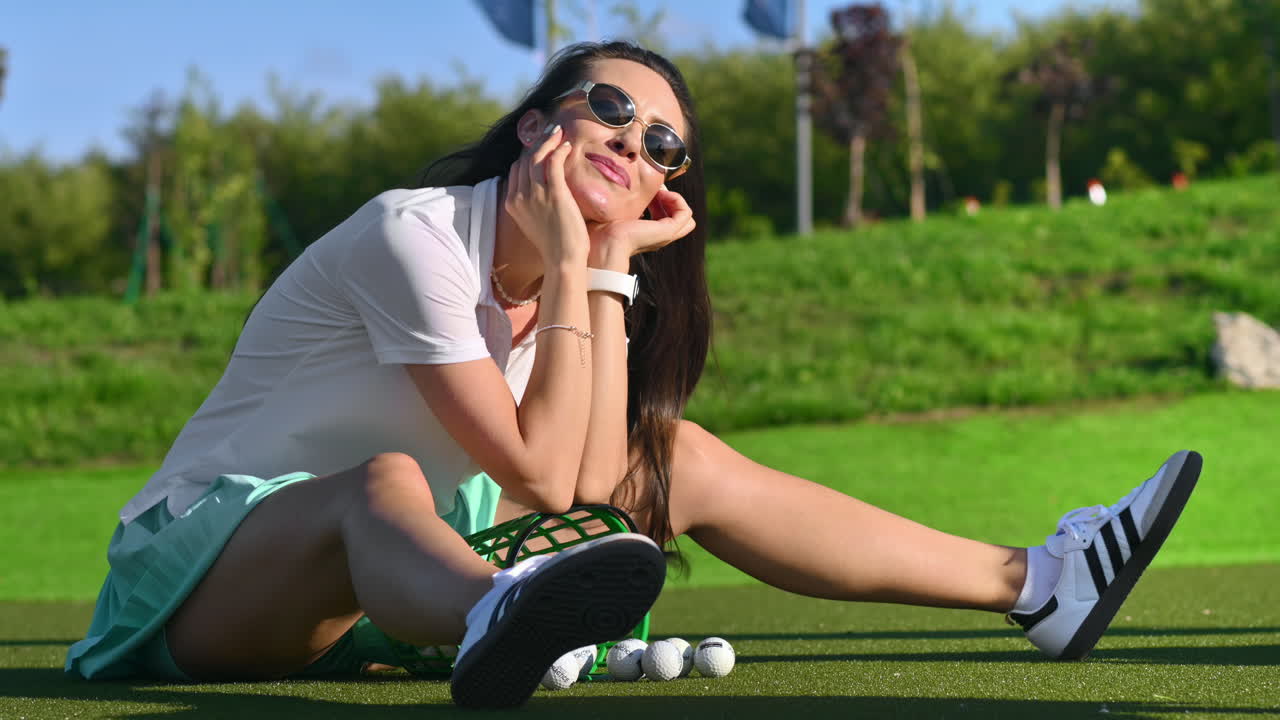 Woman in green skirt standing on the golf course near a bucket with balls