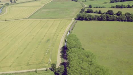 Wide-aerial-view-of-a-steam-train-leaving-Bodiam-station,-East-Sussex,-England