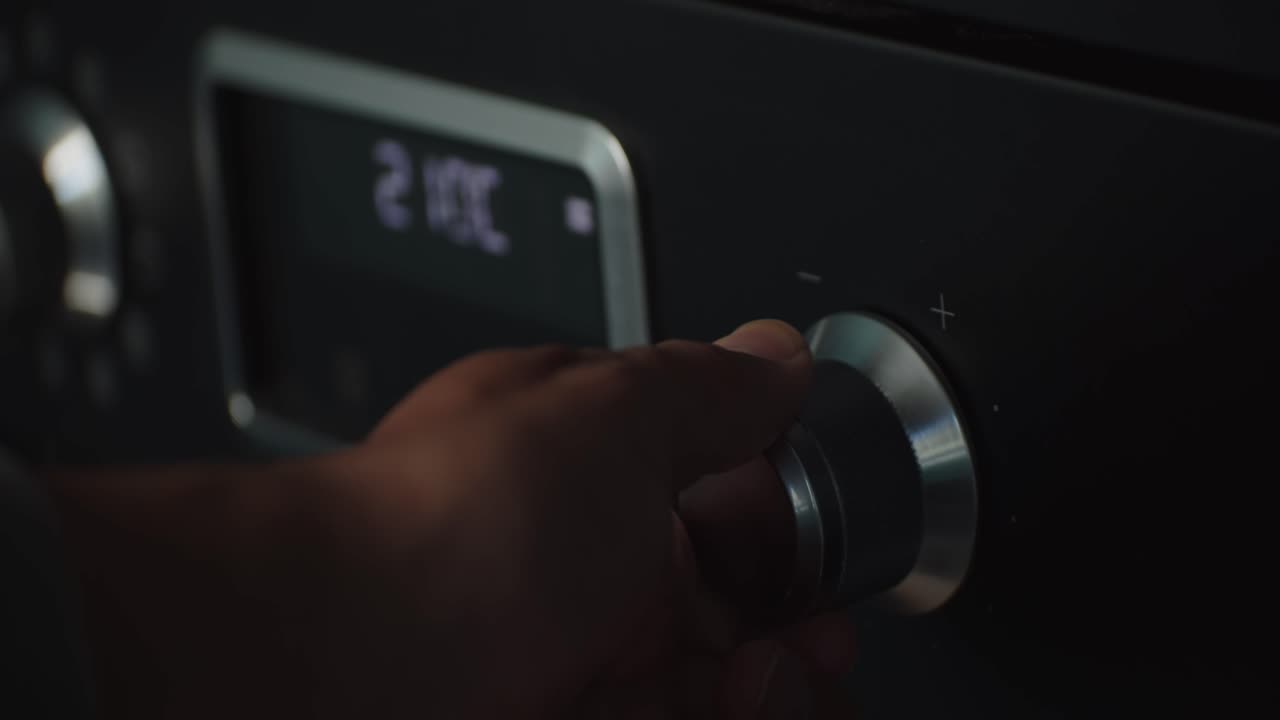 mano de persona aumentando la temperatura del horno usando la perilla, vista de cerca