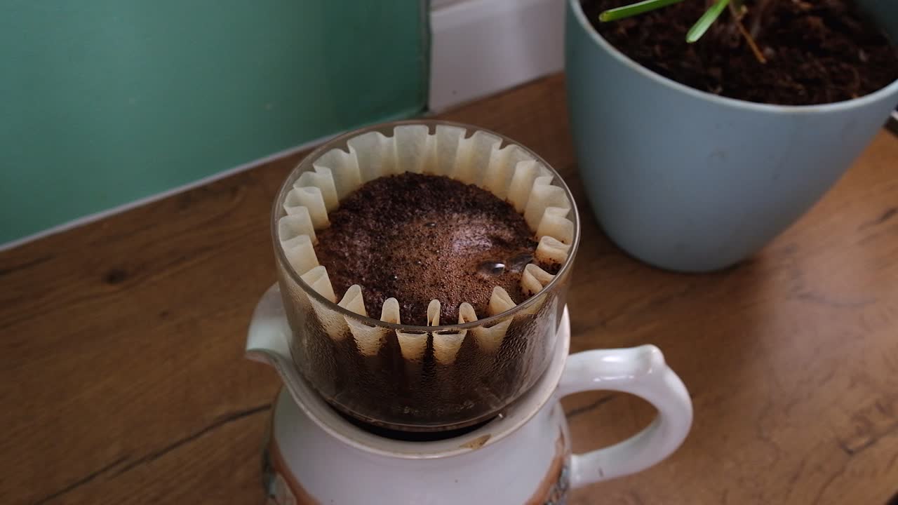 Close-up steaming hot water poured over ground coffee in basket filter