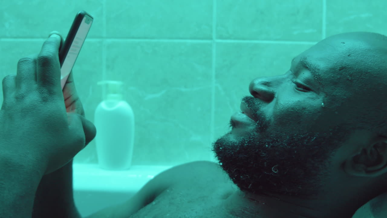 욕조 에서 휴대 전화 를 사용하는 아프리카계 미국인