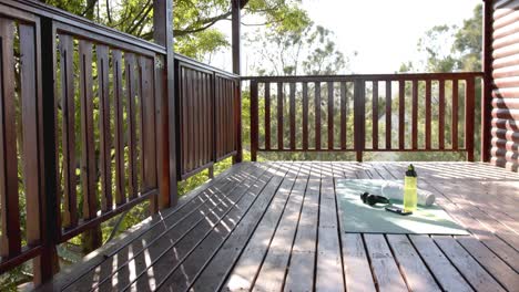 toalla, botella de agua, auriculares y teléfono inteligente en la alfombra de yoga en la cabaña de madera, cámara lenta