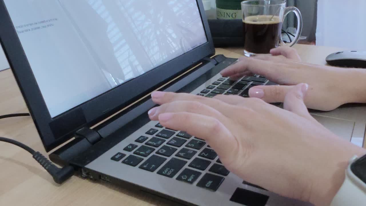 Hands focused on typing on a laptop, enhancing productivity with coffee nearby