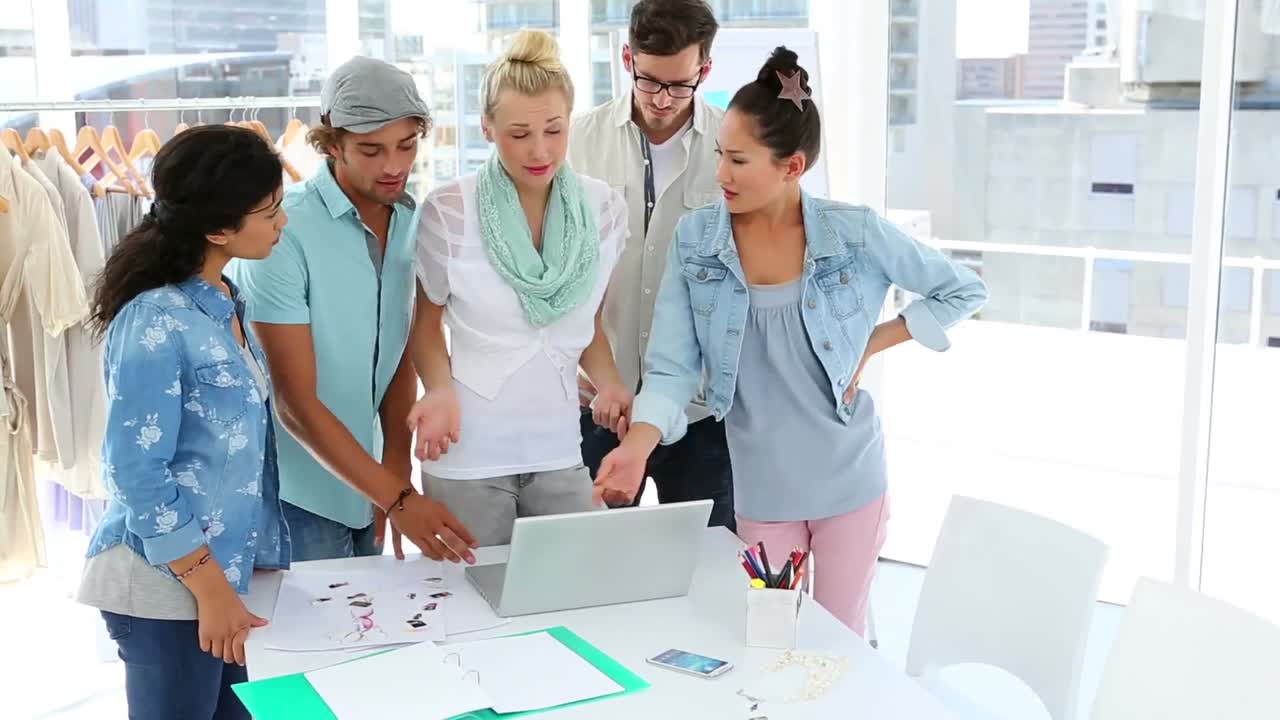 Equipo de moda haciendo una lluvia de ideas juntos usando una portátil