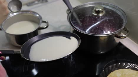 The-process-of-cooking-homemade-pancakes.-Woman-pours-pancake-dough-on-pan