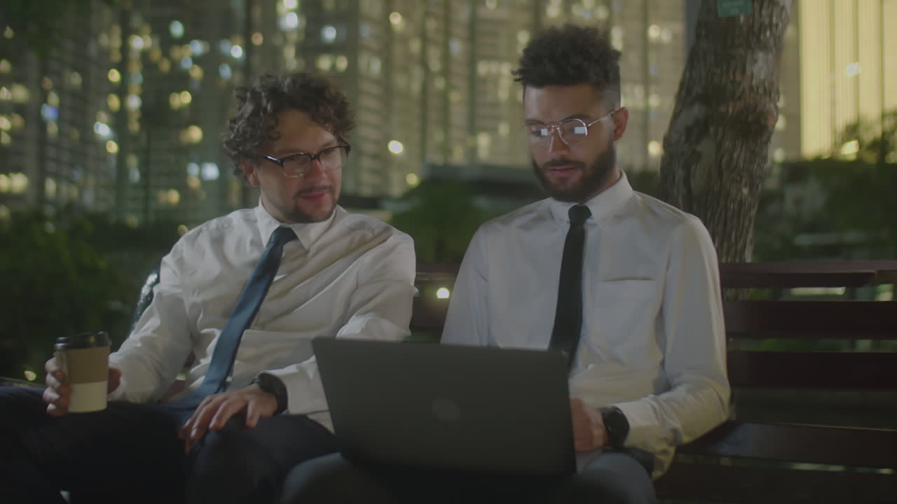Two Businessmen Working on Laptop in Park at Night