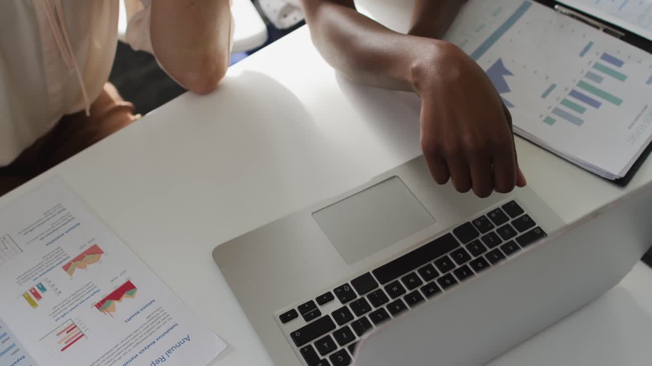 Hands of two diverse female colleagues poiting at laptop and discussing in office