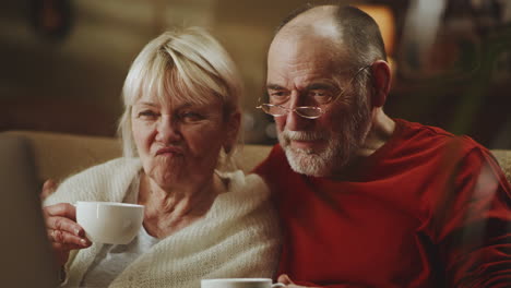 una pareja de mayores feliz usando una computadora portátil en casa