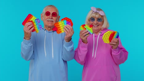 Elderly-stylish-grandmother-grandfather-showing-squeezing-anti-stress-push-pop-it-popular-toy-game