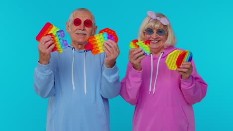 anciana abuela elegante abuelo mostrando apretando anti-estrés empujar pop es un juego de juguete popular