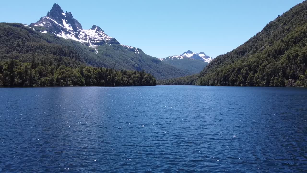 Drone footage of an amazing lake surrounded by green forest and snow mountains. Patagonia Argentina