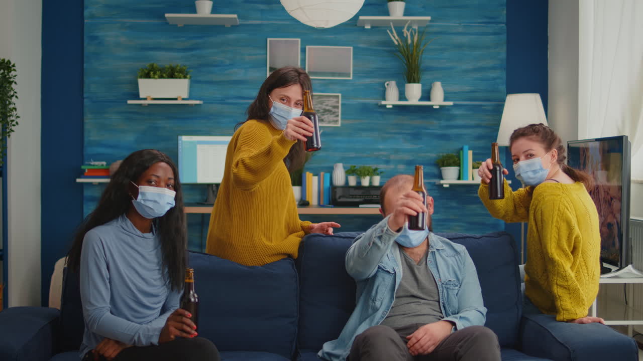 Friends with protective mask spending time in living room with online meeting