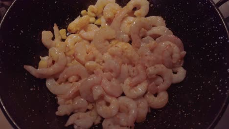 raw spanish garlic shrimp cooking in skillet with hot oil, close up