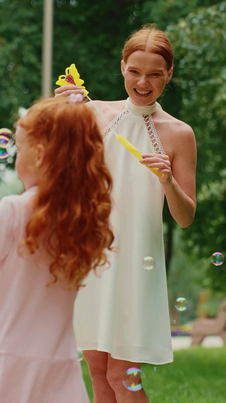 мать и дочь играют с пузырьками в парке