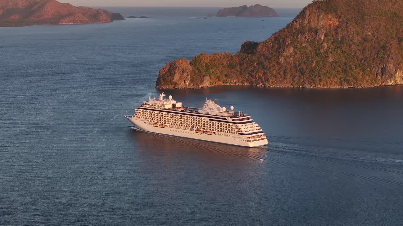 Cruise Ship On Serene Waters Of Coron, Palawan, Surrounded By Rugged Limestone Cliffs And Golden-lit Islands At Dusk. aerial shot