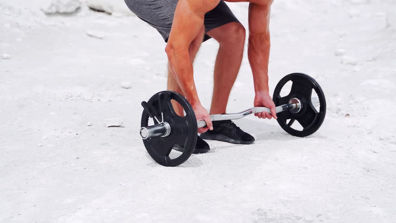 Men's hands lift the barbell from the ground. Workout in nature