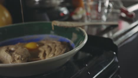 Hand-Cracking-Fresh-Egg-And-Adding-To-Cookie-Mixture-In-A-Shallow-Bowl---close-up