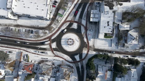 top down aerial of traffic using roundabout in winter - drone slowly setting down