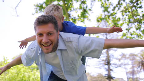 A-father-sways-from-side-to-side-while-giving-his-son-a-piggy-back-with-his-arms-spread