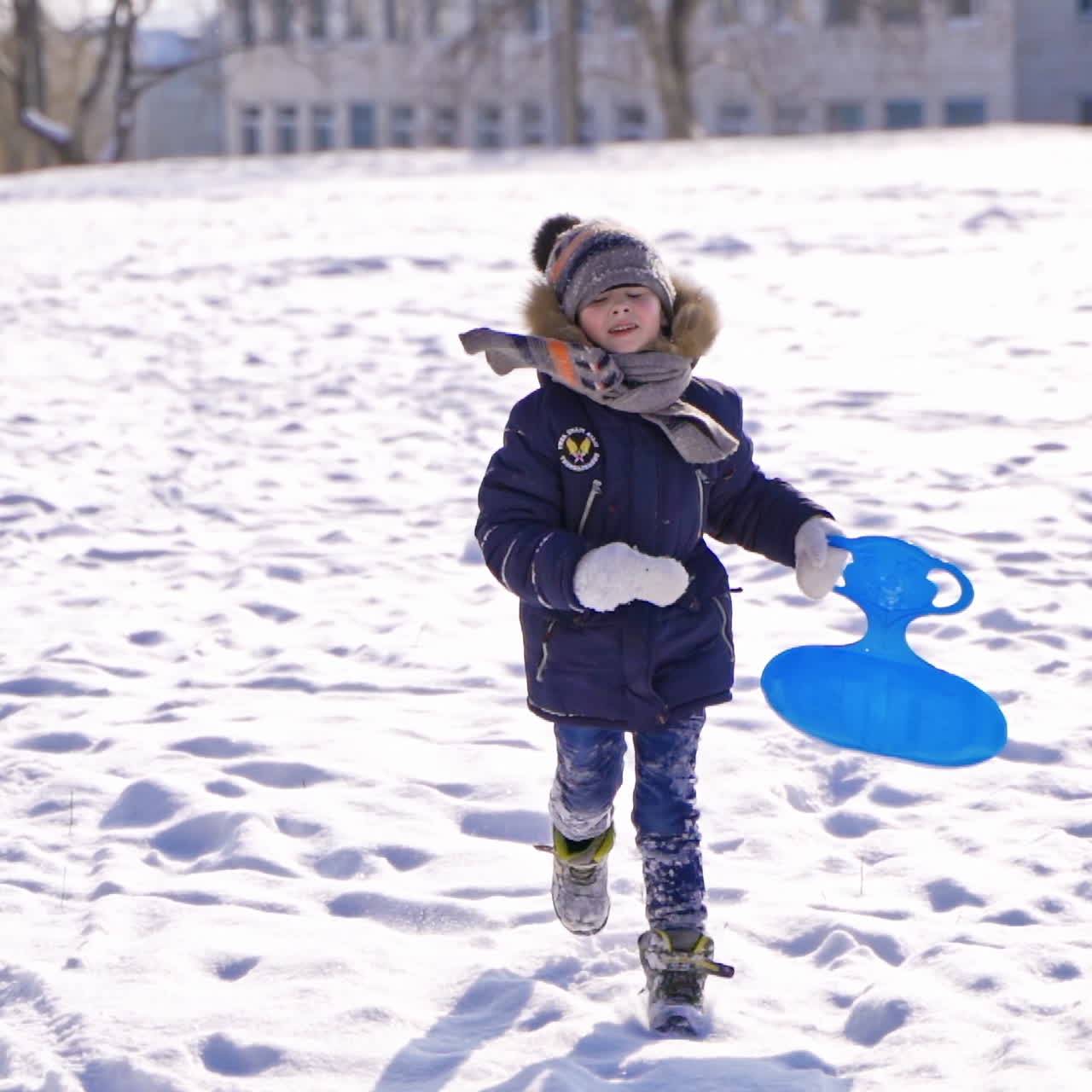 child boy having fun, playing and laughing on snowy winter walk in nature. Frost winter season.Cute little boy with saucer sleds outdoors on winter day, ride down the hills, winter games and fun