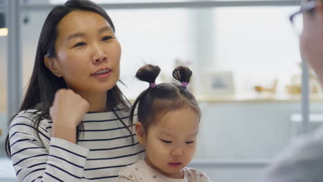 asian woman with child having talk with pediatrician