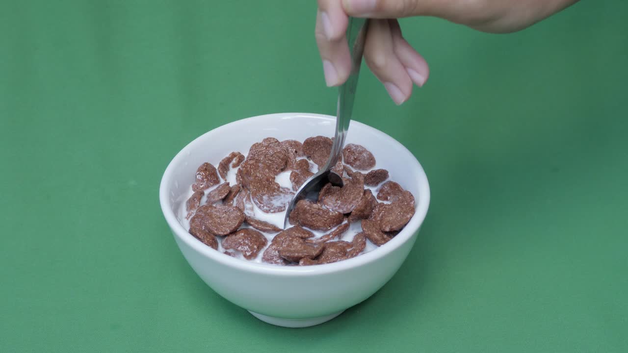 녹색 스크린 배경의  그에 천천히 움직이는 초콜릿 옥수수 어리와 신선한 우유를 는 아침 식사를합니다.