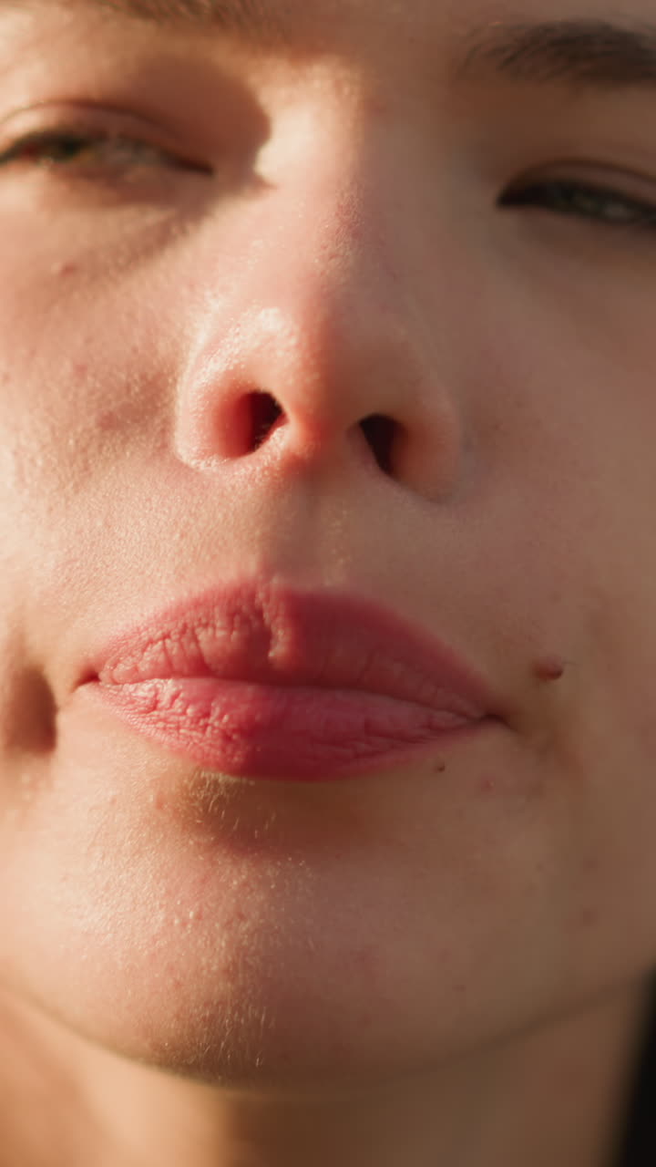 primer plano de una mujer bebiendo jugo de naranja de una botella de plástico al aire libre, con la luz del sol brillando en su cara, la botella y el suave brillo de fondo de luz y vegetación, reflejando satisfacción