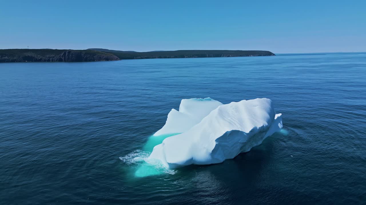 Aerial footage of a large iceberg off Flatrock, Newfoundland, featuring vivid turquoise meltwater in calm Atlantic waters.