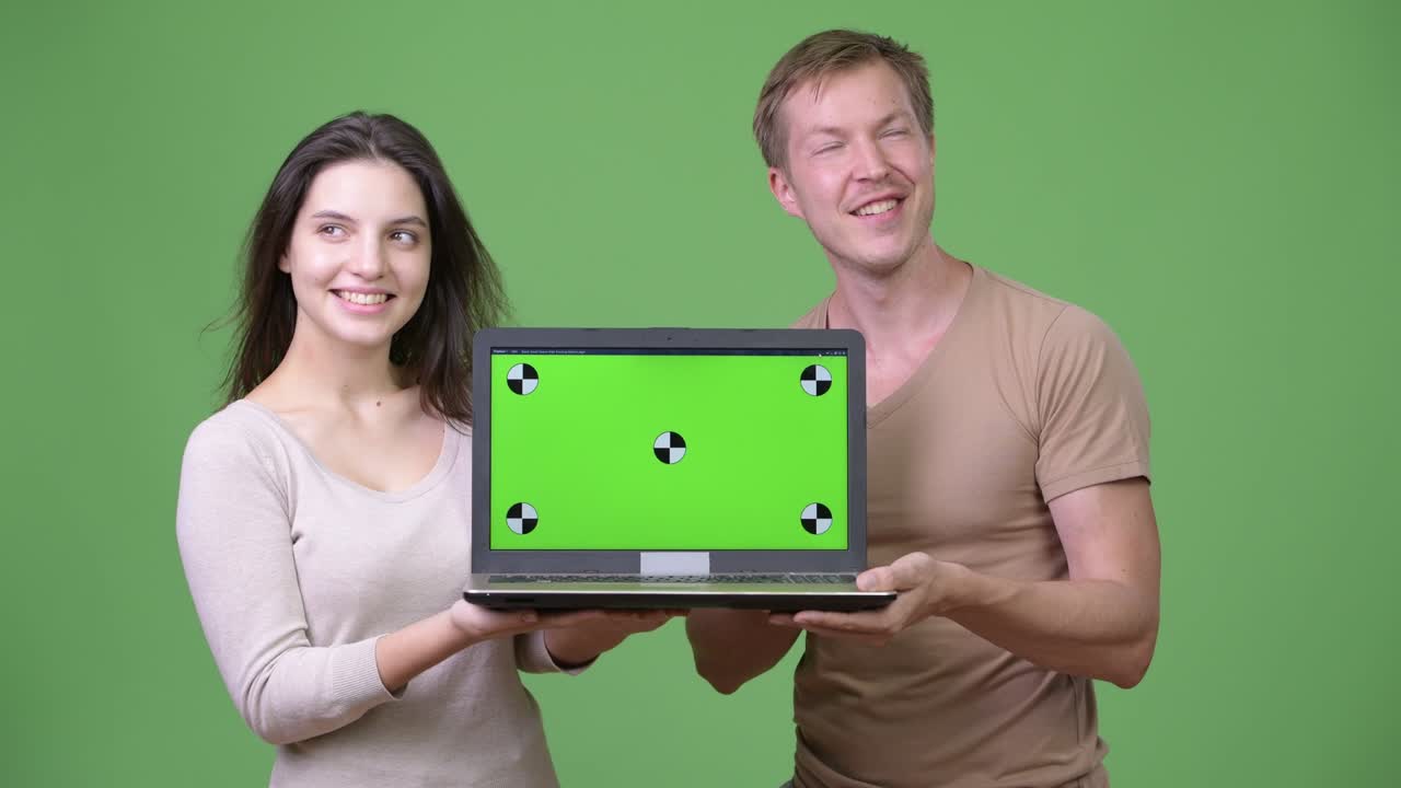 Young happy couple showing laptop and thinking together