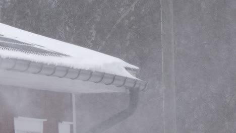 heavy snowfall on rooftop of private home with forest background