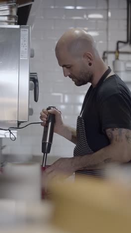 chef preparing food with an immersion blender in a kitchen