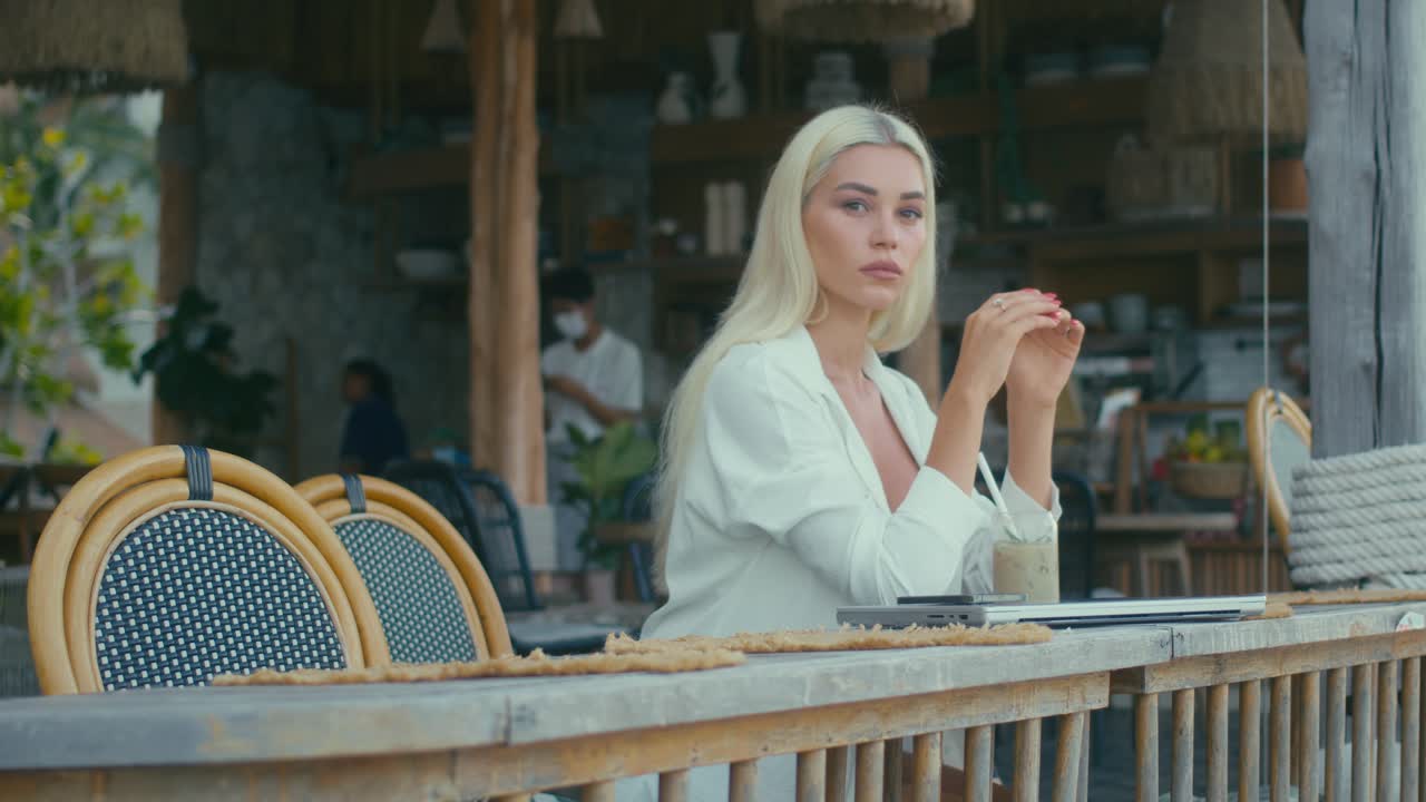Woman working on laptop in a tropical cafe