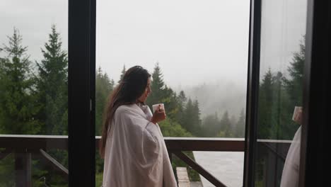 woman enjoying a coffee on a rainy mountain balcony