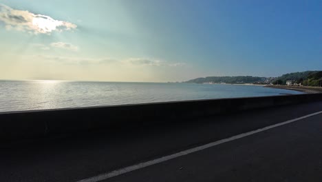 view from walking and cycling promenade in swansea bay in the morning with vibrant blue sky as bay arches around with sea at high tide