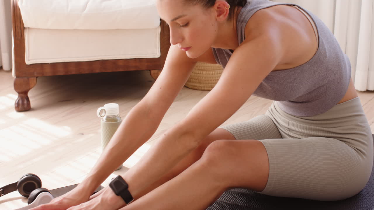 Woman stretching on yoga mat at home, focusing on flexibility and wellness