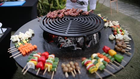 chef preparing meat and vegetable skewers on grill