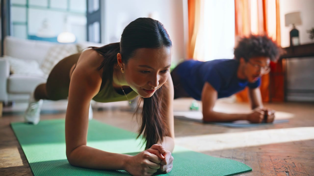 Multiethnic couple holding plank position on mats during home fitness workout