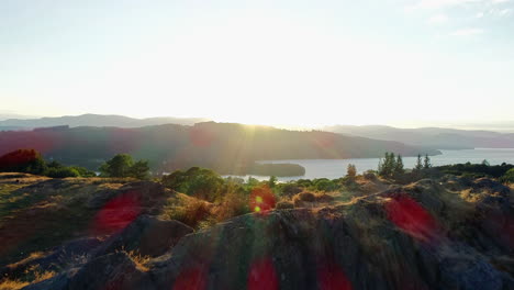 drone shot of rolling green hills, trees and lake windermere in sunlight with lens flare, lake district, uk