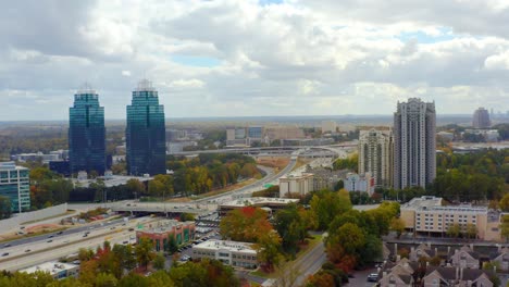 Aerial-shot-of-the-King-and-Queen-towers-in-Atlanta-with-highway-and-traffic