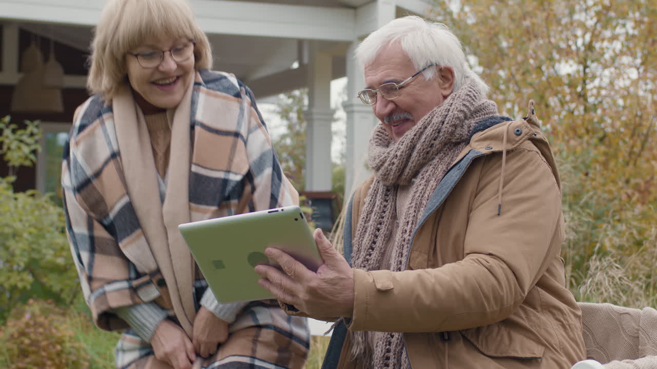 Elderly Couple Enjoying Tablet Outdoors in Autumn