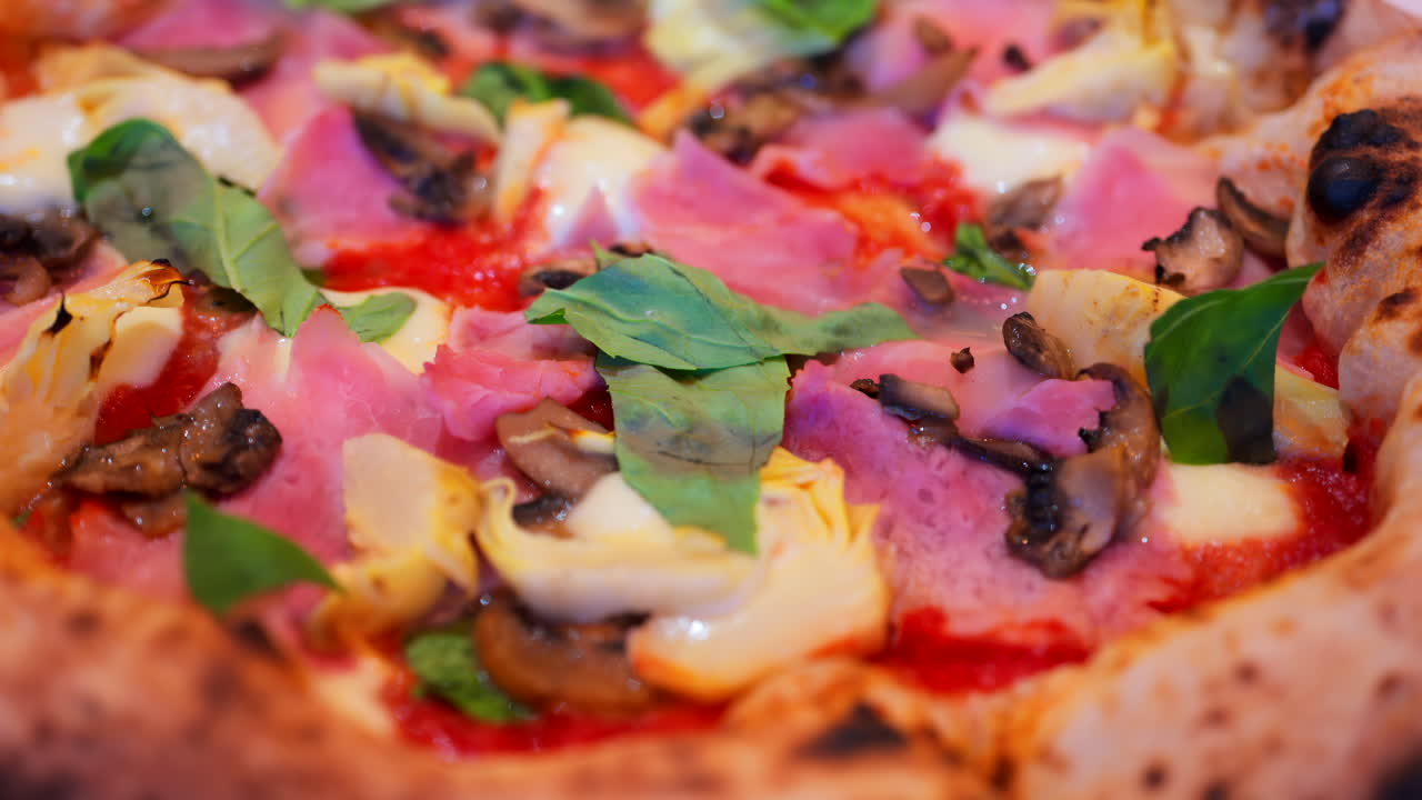 Close up of pizza with artichoke, ham, mushrooms and basil