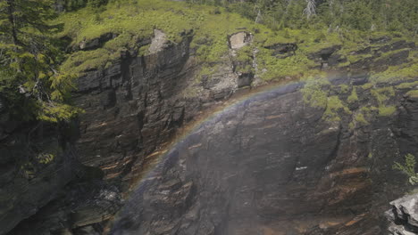 breathtaking-rainbow-formed-in-the-mist-inside-a-huge-and-deep-rocky-canyon-partially-covered-by-vegetation