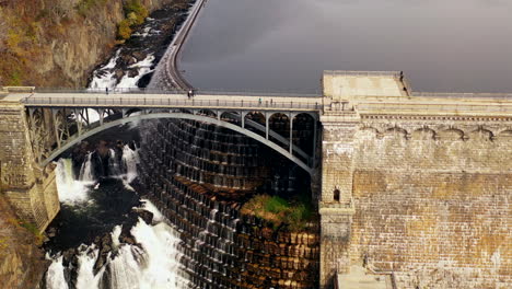 pedestal shot up as the drone camera tilts down - dolly out away from the waterfalls - overpass at the new croton dam in westchester county, ny