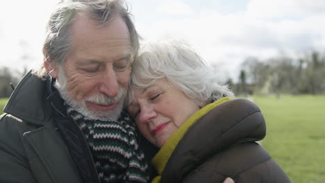 loving senior couple hugging on autumn or winter walk through park together